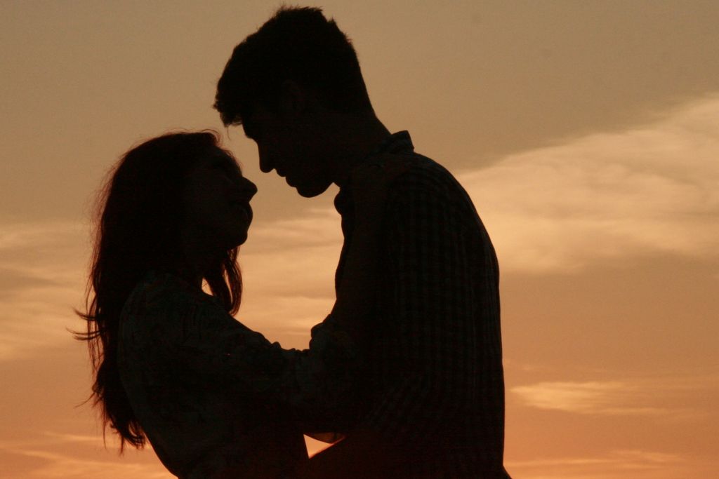 A couple enjoying a sweet silhouette during sunset.