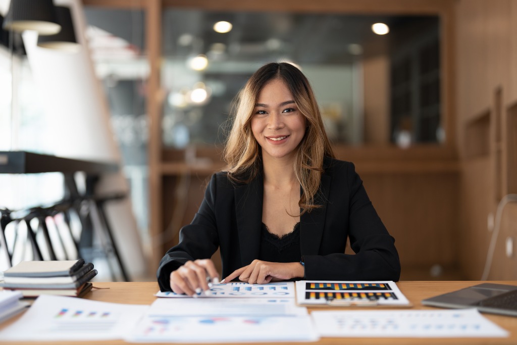 A woman is smiling and doing her finances