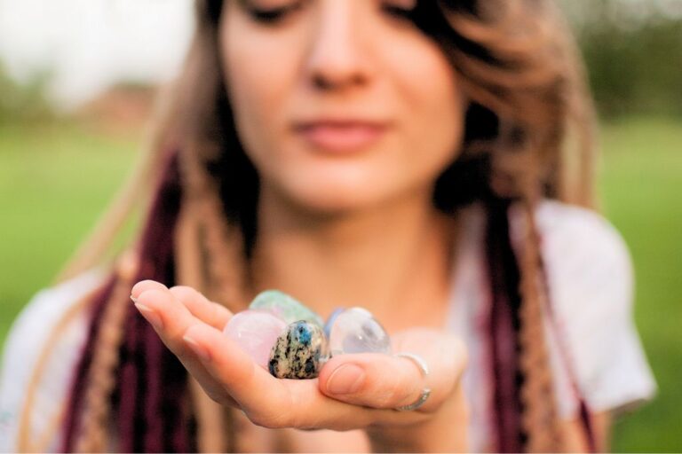 A woman is holding several crystals on her palm.