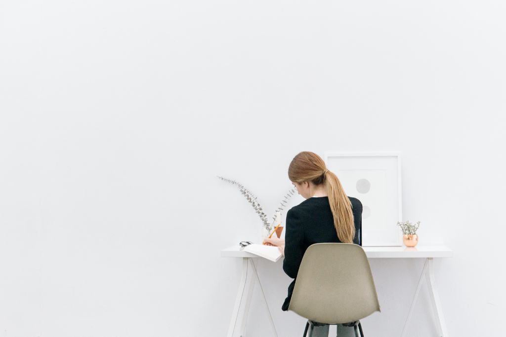 woman sitting in a chair writing on a notebook