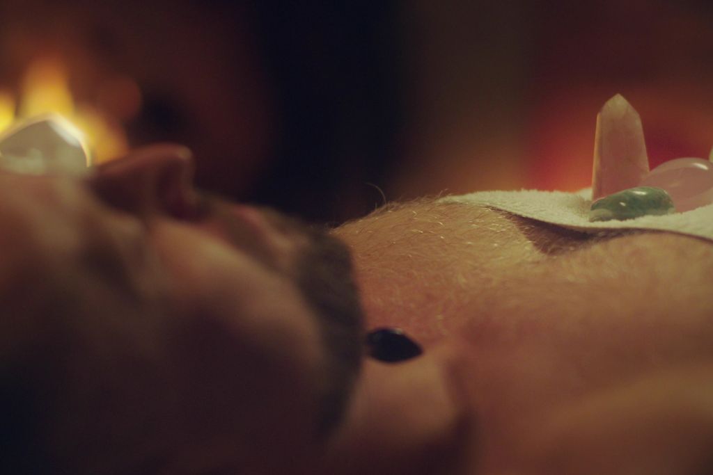 young man relaxing after crystal massage with fireplace background