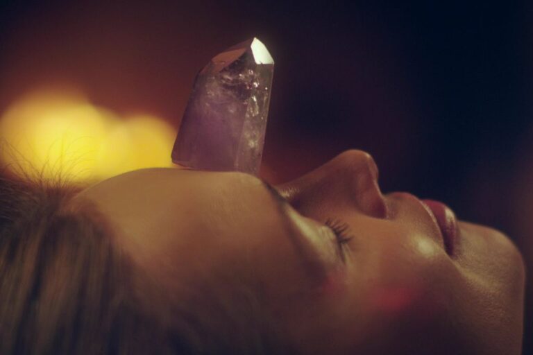 young woman relaxing after crystal massage with amethyst tower on top of her head