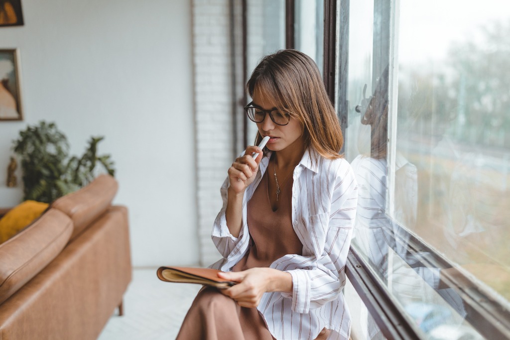 A woman is thinking near the windows