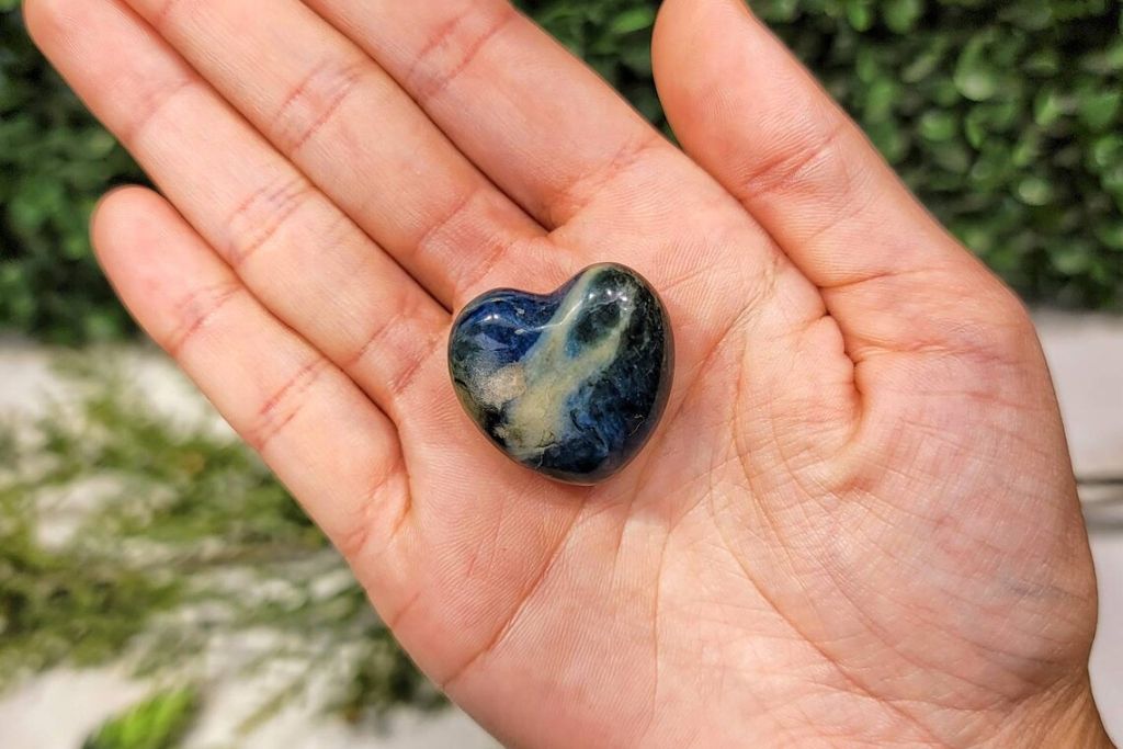 A heart shape Dianite Crystal on a palm of a person. Source: Etsy | LovingThyselfRocks