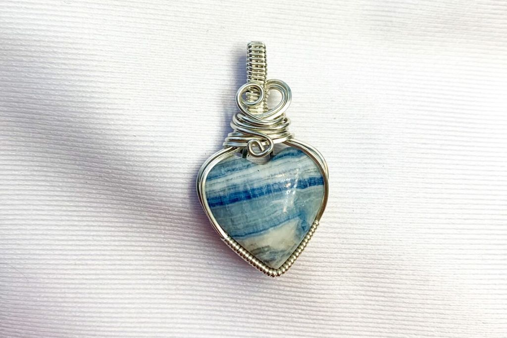 A Lapis Lace Onyx pendant on a white cloth. Source: Etsy | WorthyofLoveJewelry