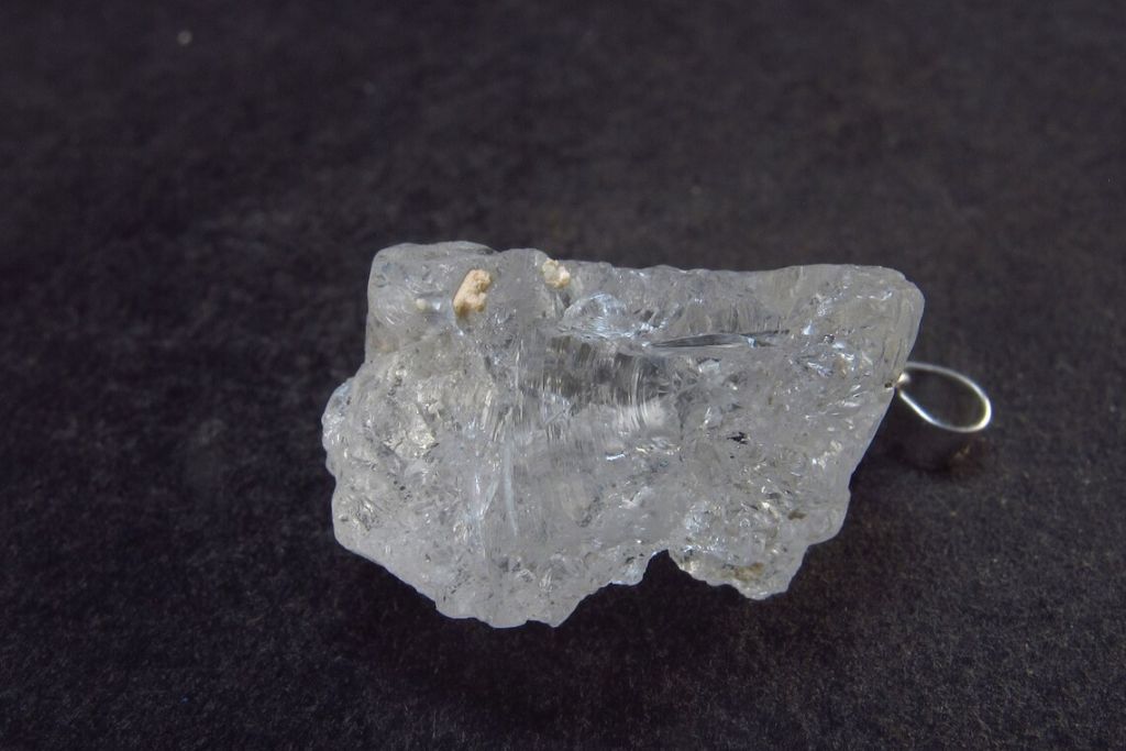 A Pollucite pendant on a greyish background. Source: Etsy | TheGlobalStone