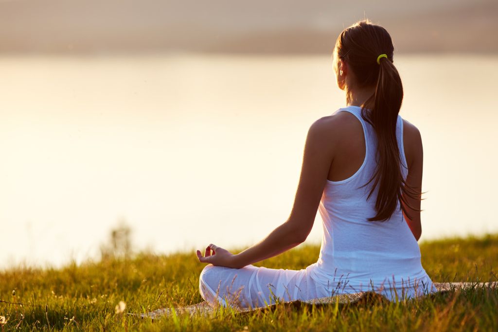 a woman sitting on the grass doing meditation