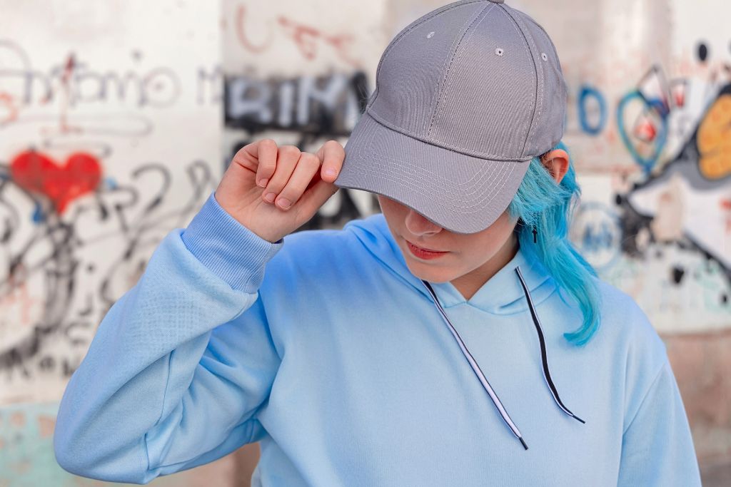 woman blue hair, with blue cap, and wearing blue hoodie jacket