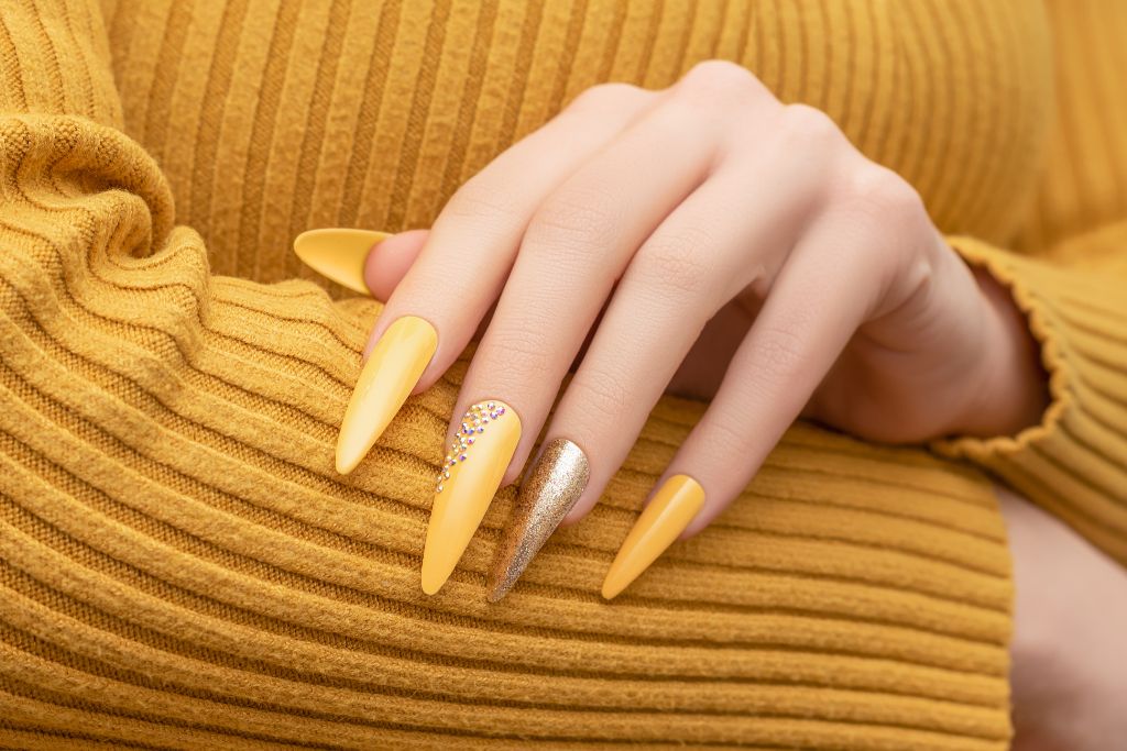 female hand with yellow nail polish