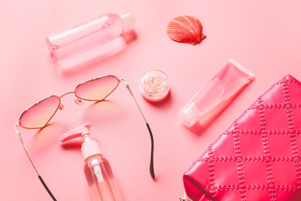 Pink accessories are arranged in flatlays on a pink-painted table.