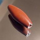 elongated pipestone bead on a glass table