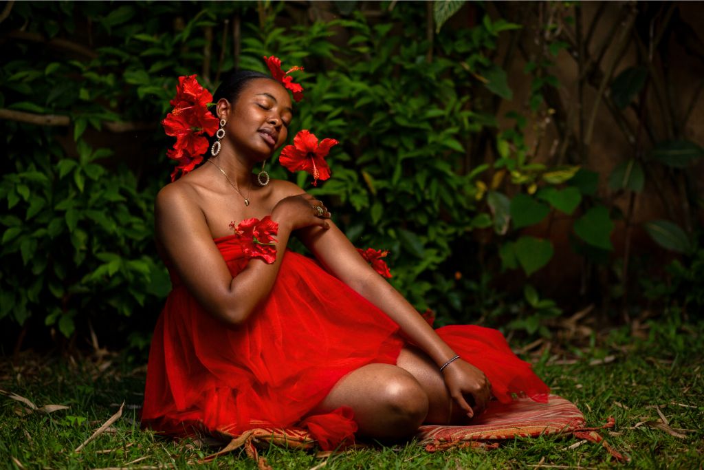 A woman wearing a red dress sitting on the grass in nature