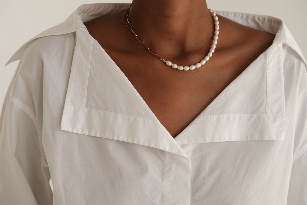 a woman in a casual shirt wearing a pearl necklace