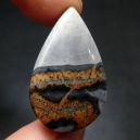 finger tips holding a teardrop shape Agate Jasper on a dark background