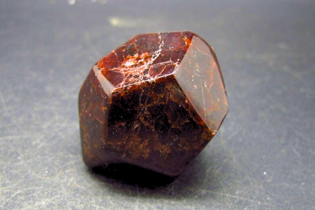 Almandine Garnet from Adelaide Crystal placed on grayish table. Image Source: Etsy.com | Mike Petrov - TheGlobalStone