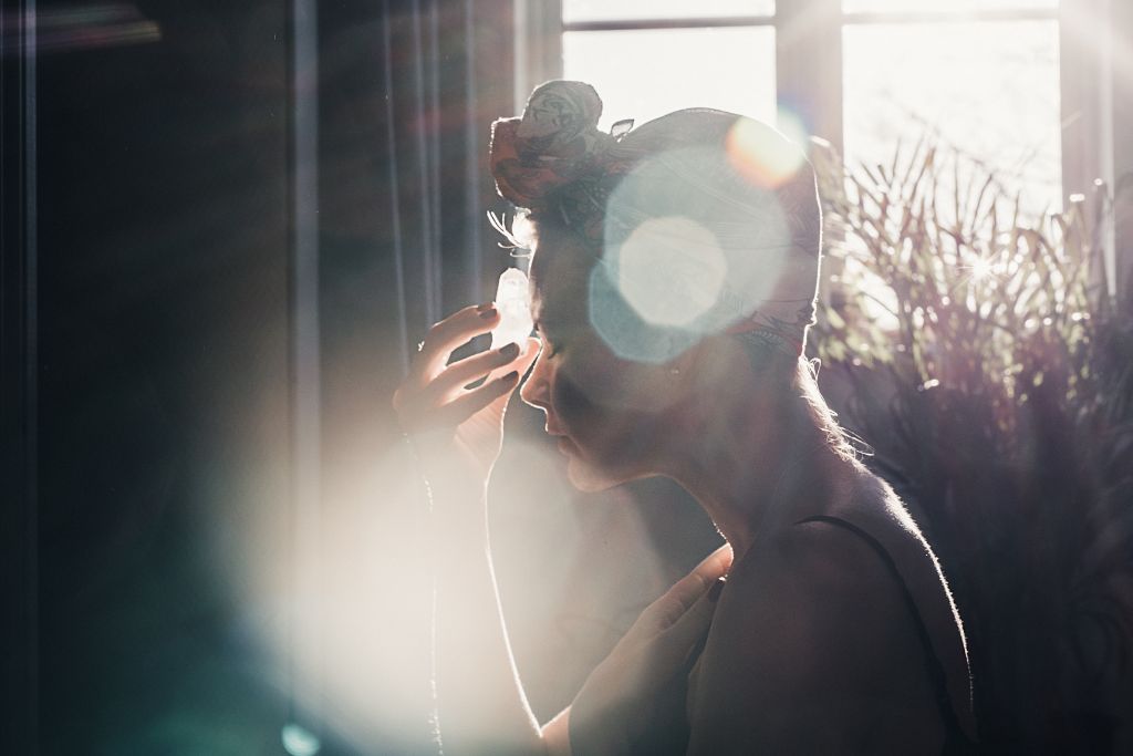 A woman meditating while touching a crystal in her forehead. 