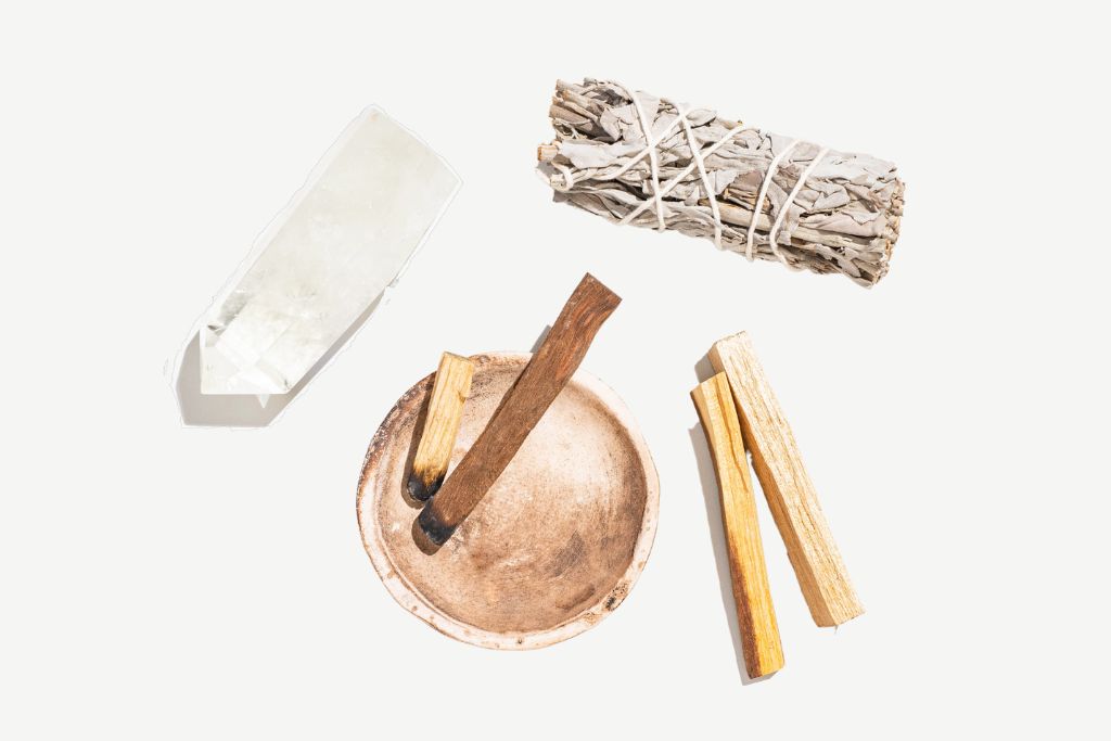 Clear Quartz, Singing Bowl, Sage, and Palo Santo on a pitch white background. 