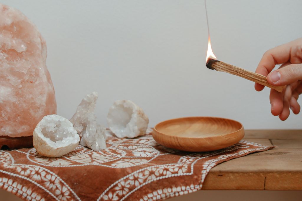 Different crystals and an smoking sage on top of a table.