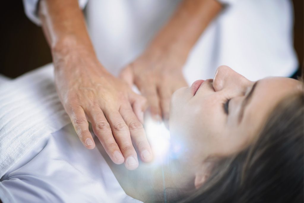 a woman lying down white a pair of hand holding her throat