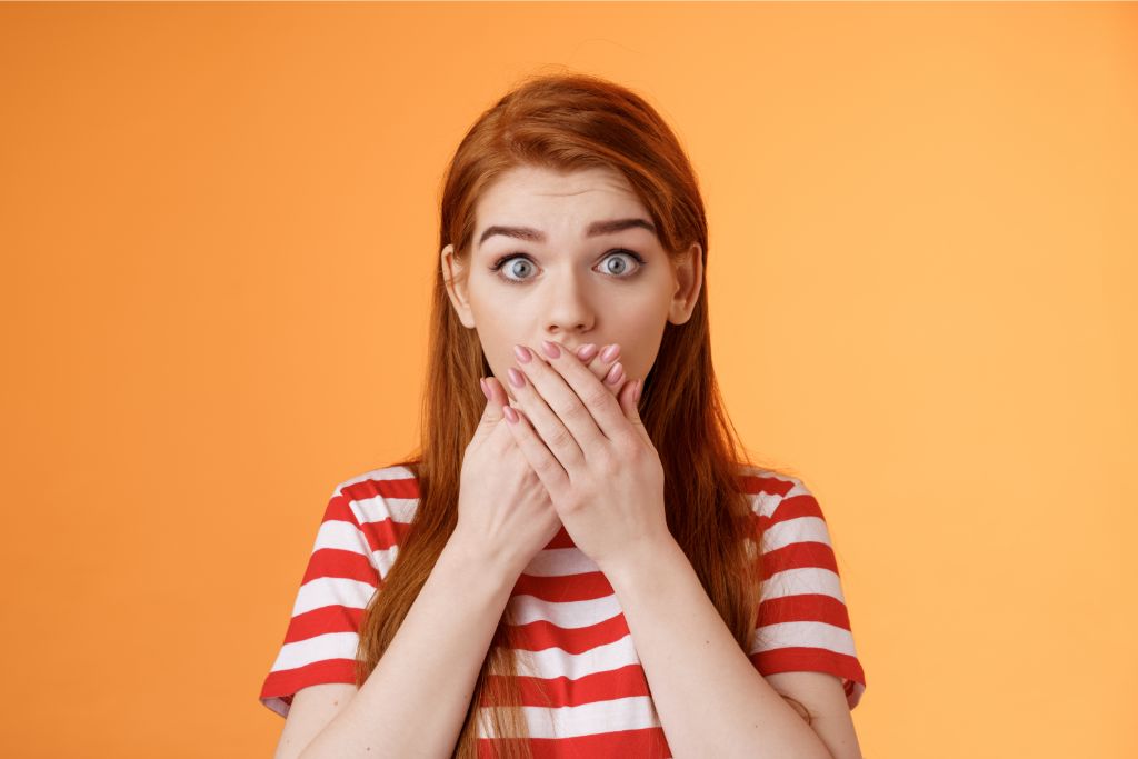 astonished female model wearing red and white striped shirt on orange background