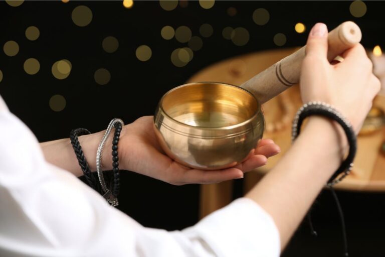 woman using singing bowl in sound healing on black background