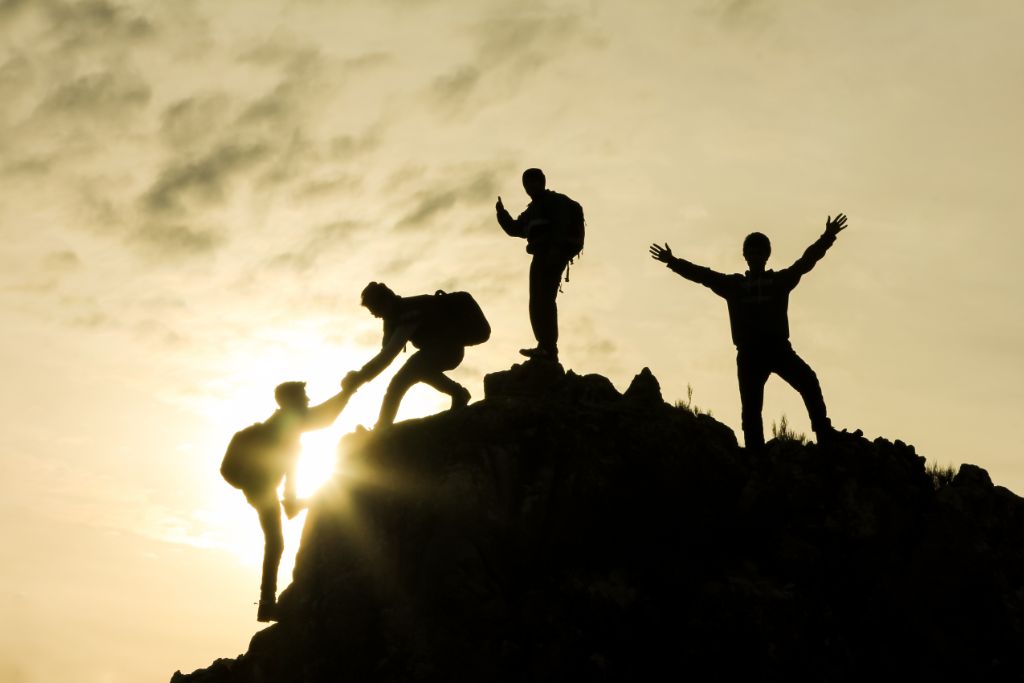 People helping each other climb a mountain