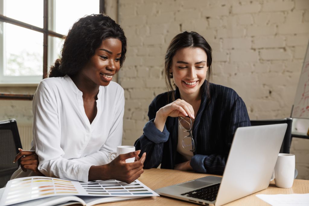 Two women looking at a laptop smiling.