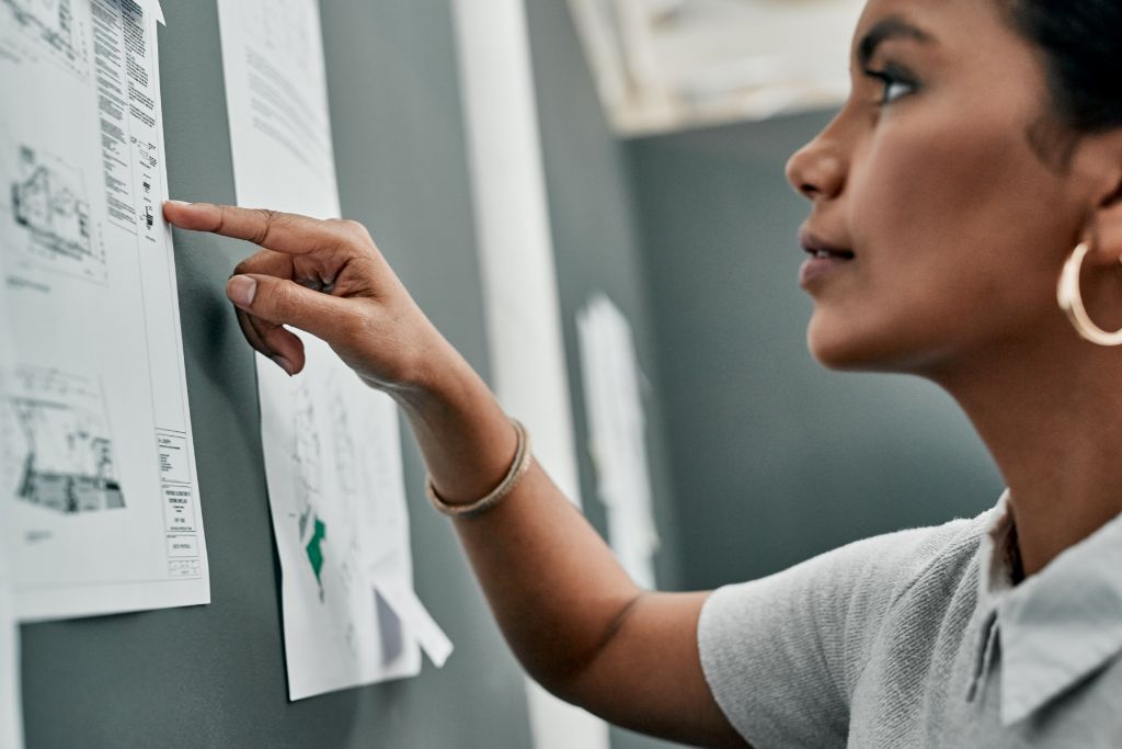 A woman paying attention to every single written in a paper posted in a board.