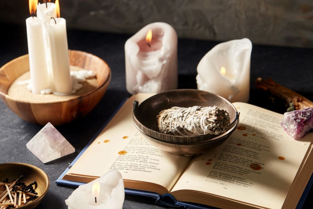 candle, sage and book on the table