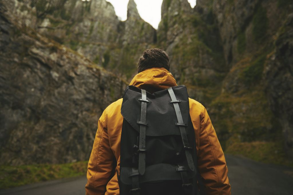 a guy with a yellow coat and wearing a backpack