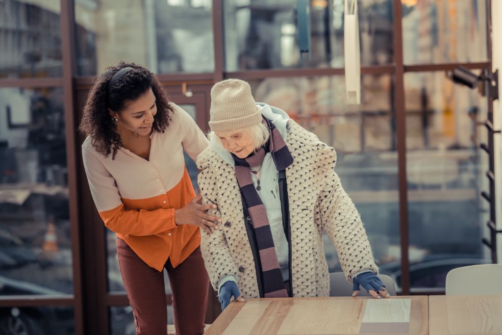 A kind young woman helping an old lady