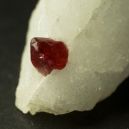 red spinel on calcite lying on dark background