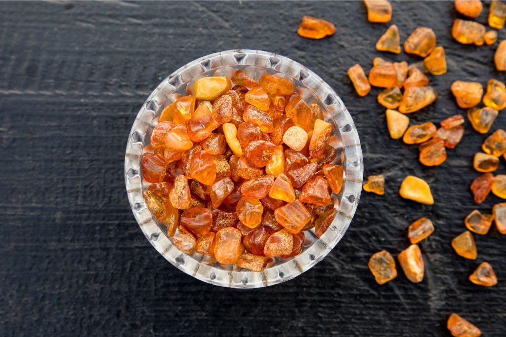 semi polished baltic amber stones on white cup placed on top of a wooden table