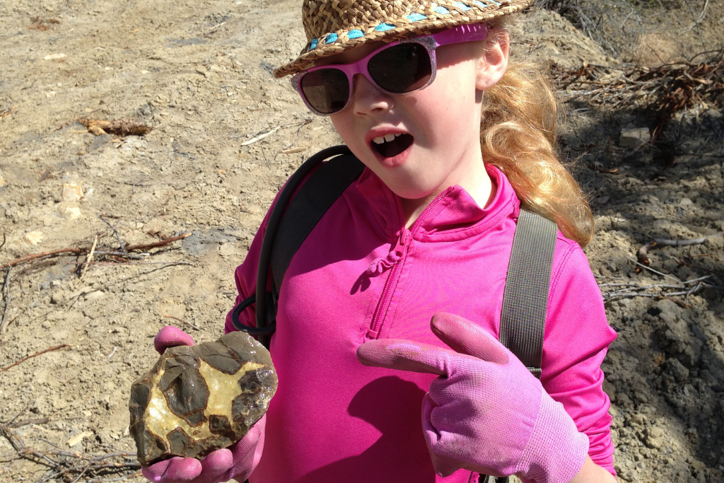 a female child holding a newly found stone from doing rockhound