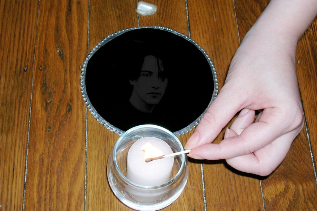 a scrying mirror, a crystal, and a hand about to light a candle 