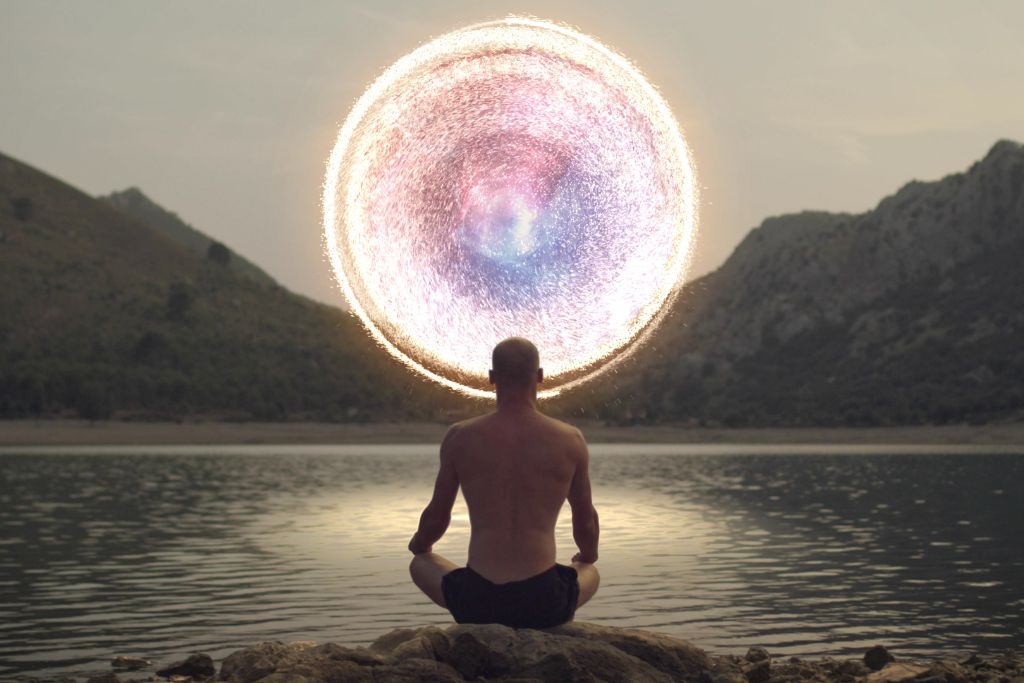 a man sitting by a body of water with a cosmic object in front depicting cosmic wisdom