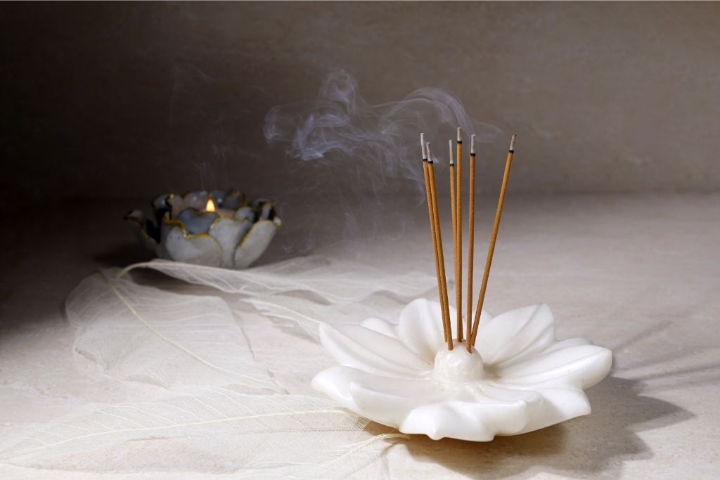 Smoking incense sticks on top of a flower petal design