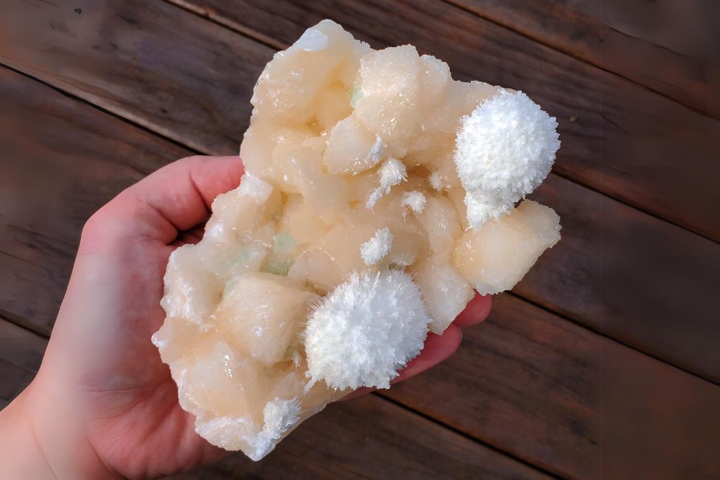 a hand holding White Mordenite on Peach Stilbite