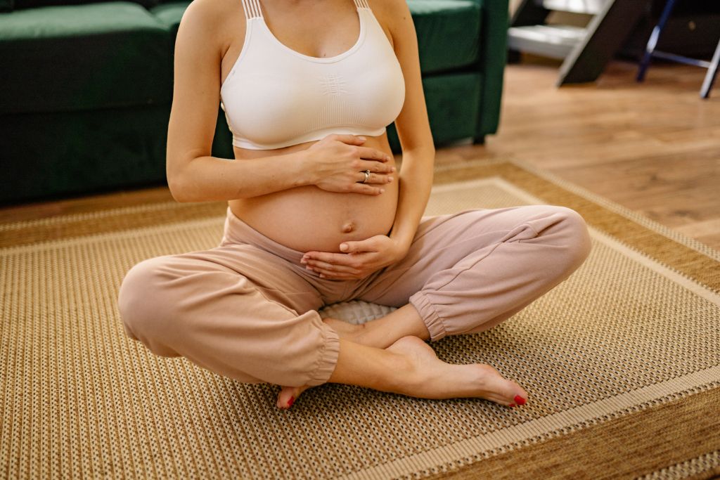 a woman holding her baby bump while sitting on a squat position