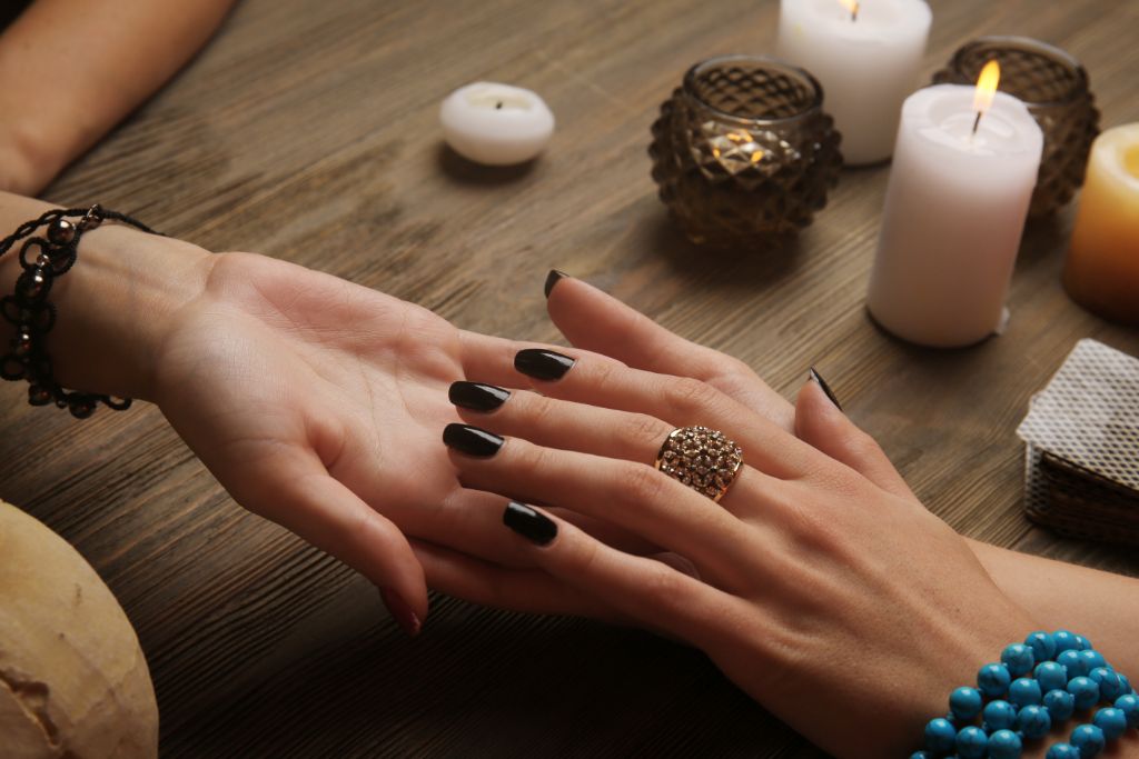 two hands on the table surrounded by candles showing psychic protection