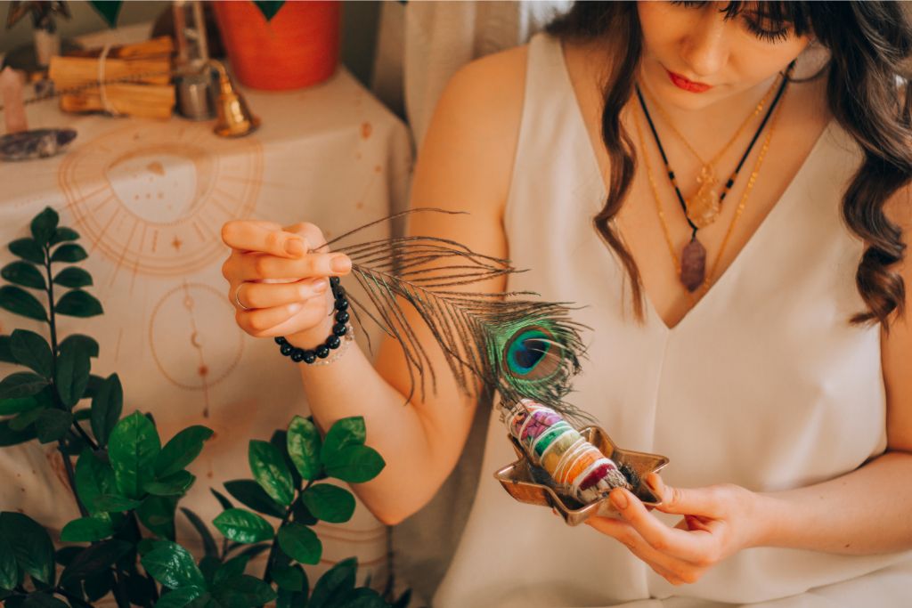 girl holding a peacock feather and plants depicting smudging with plants