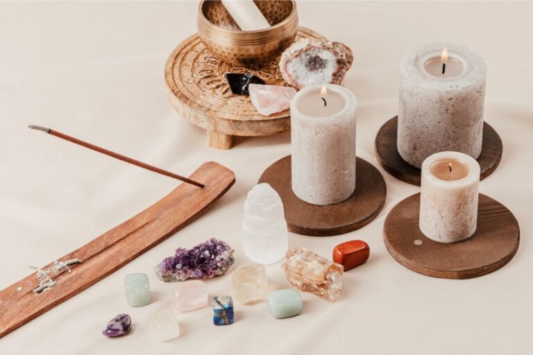 candles, crystals and singing bowl placed on a white surface