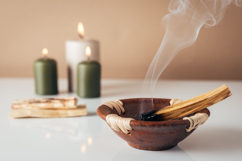 lit palo santo and candle on the background