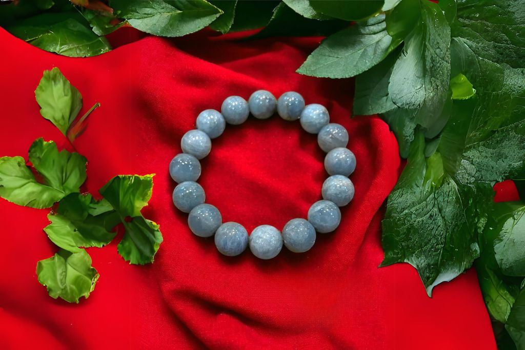 cat'e eye aquamarine bracelet on red cloth surrounded by leaves