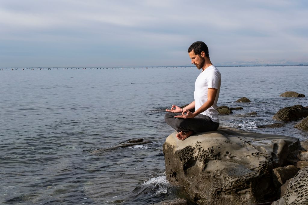 Man meditating with ocean background