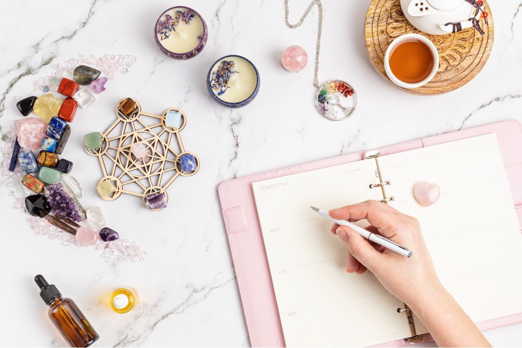 a hand holding a pen in an altar with crystals and candle