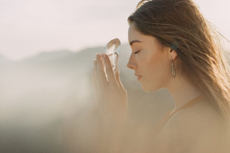 woman holding crystal toward hers forehead