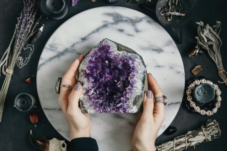 woman holding large amethyst geode on marble disc