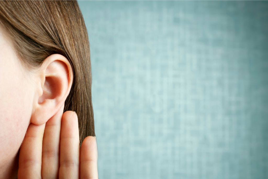 a person listen attentively with palm behind her ear