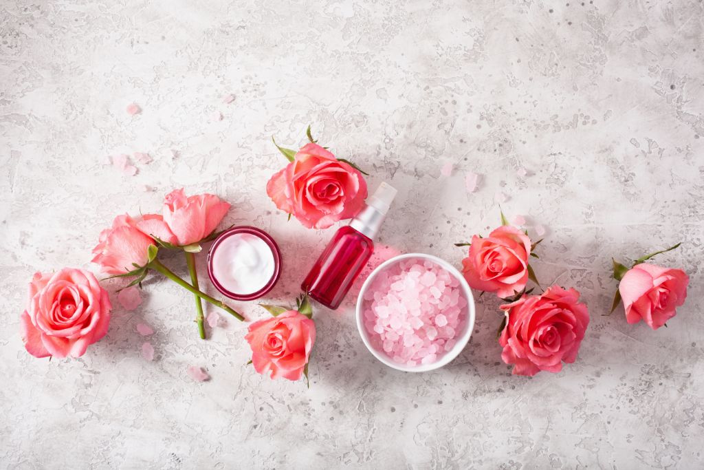 scrub, spray and lotion with roses on marble background